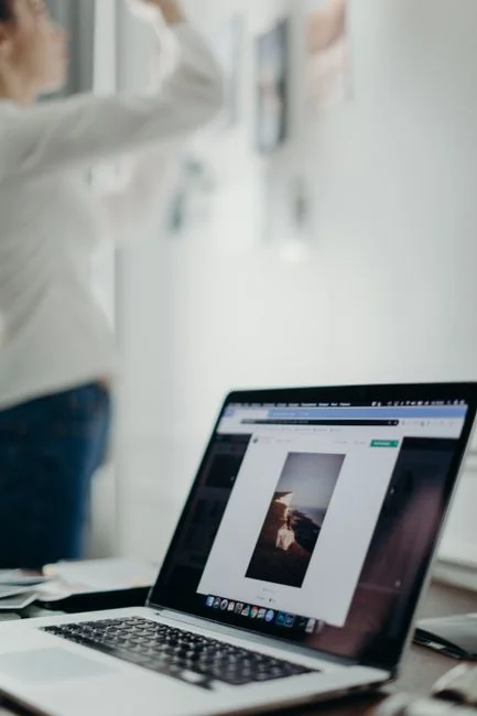 A modern workspace showing hands analyzing marketing data on a laptop and paper documents.